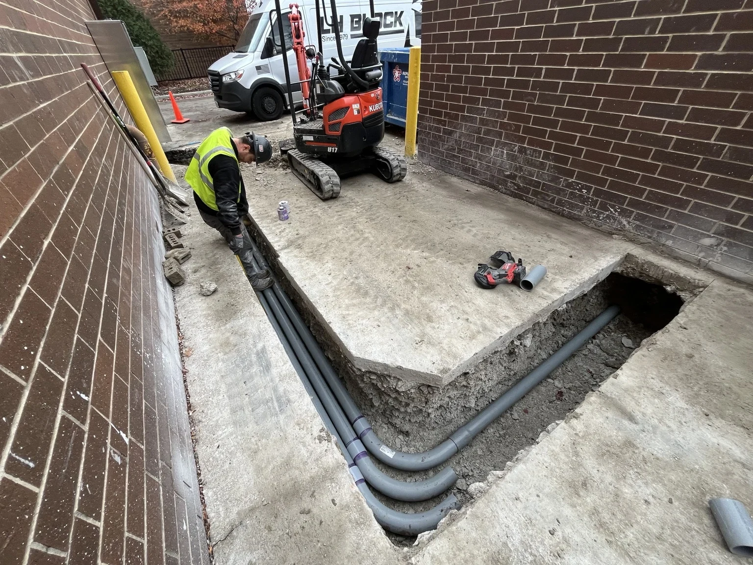 Underground conduits installed in an exterior trench beside the building.