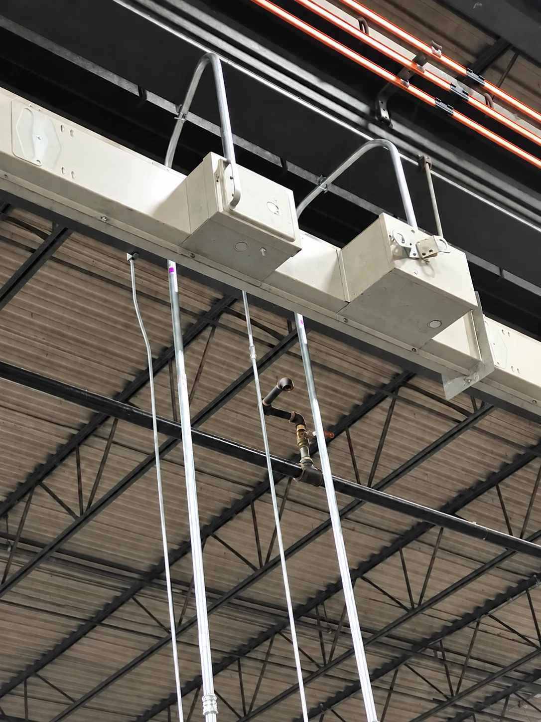 Close-up of overhead bus duct switches with conduit connections near the crane runway.
