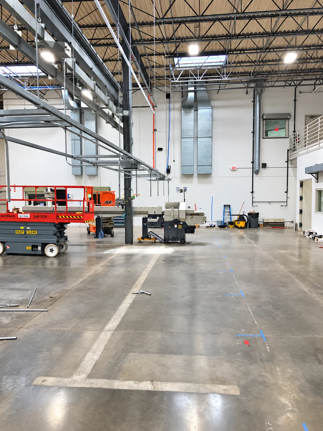 Overhead racks and conduit installed above the shop floor during the equipment relocation.