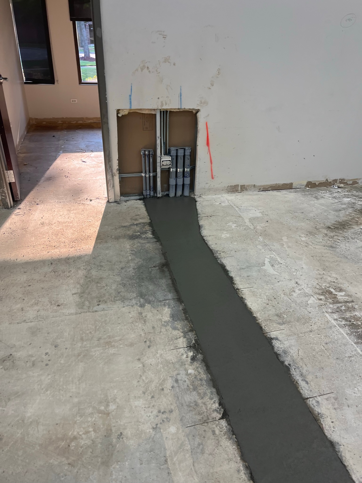 Restored concrete trench at the wall conduit stub-ups, before final floor finishes.
