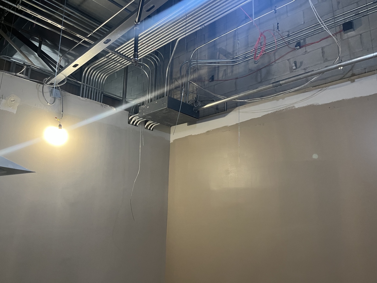 Overhead conduit routes and a junction box above the office walls.