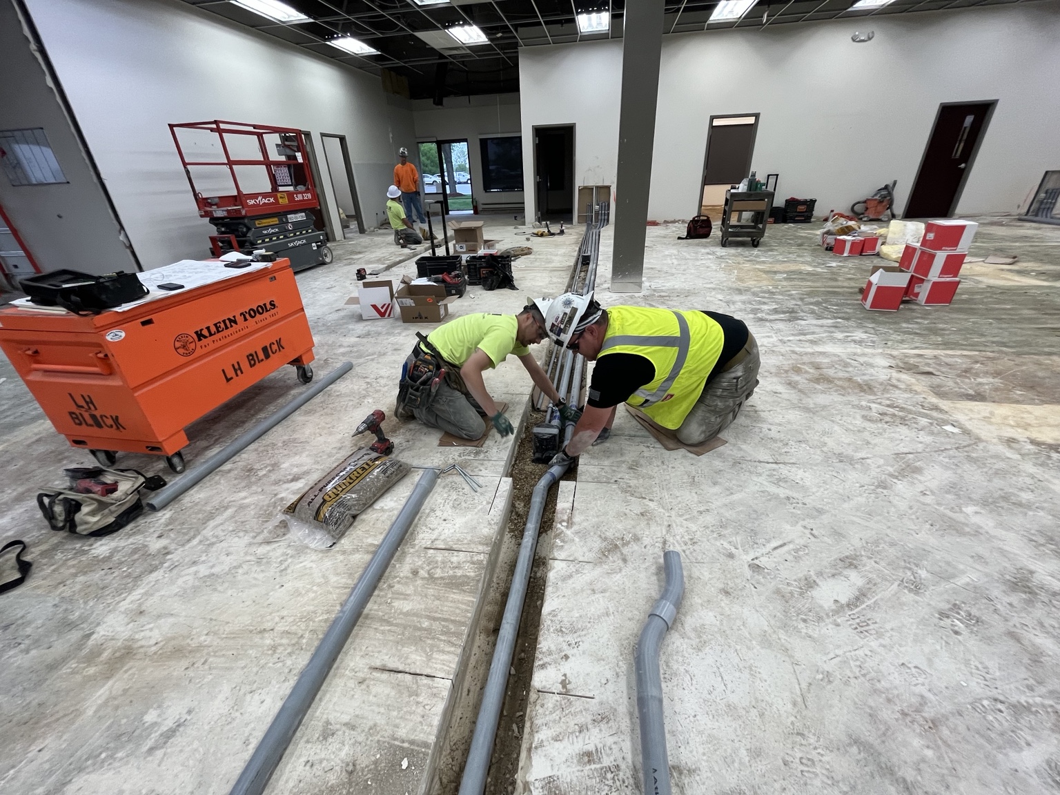 LH Block electricians installing conduit beneath the existing office floor at Crown Lift Trucks.