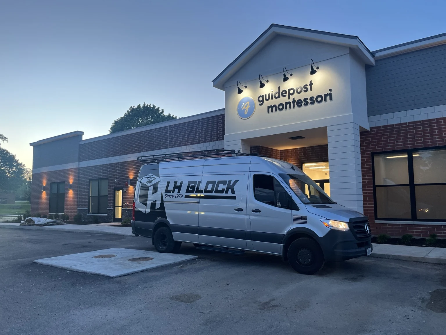 Guidepost Montessori in Vernon Hills with illuminated exterior fixtures and an LH Block Electric van.