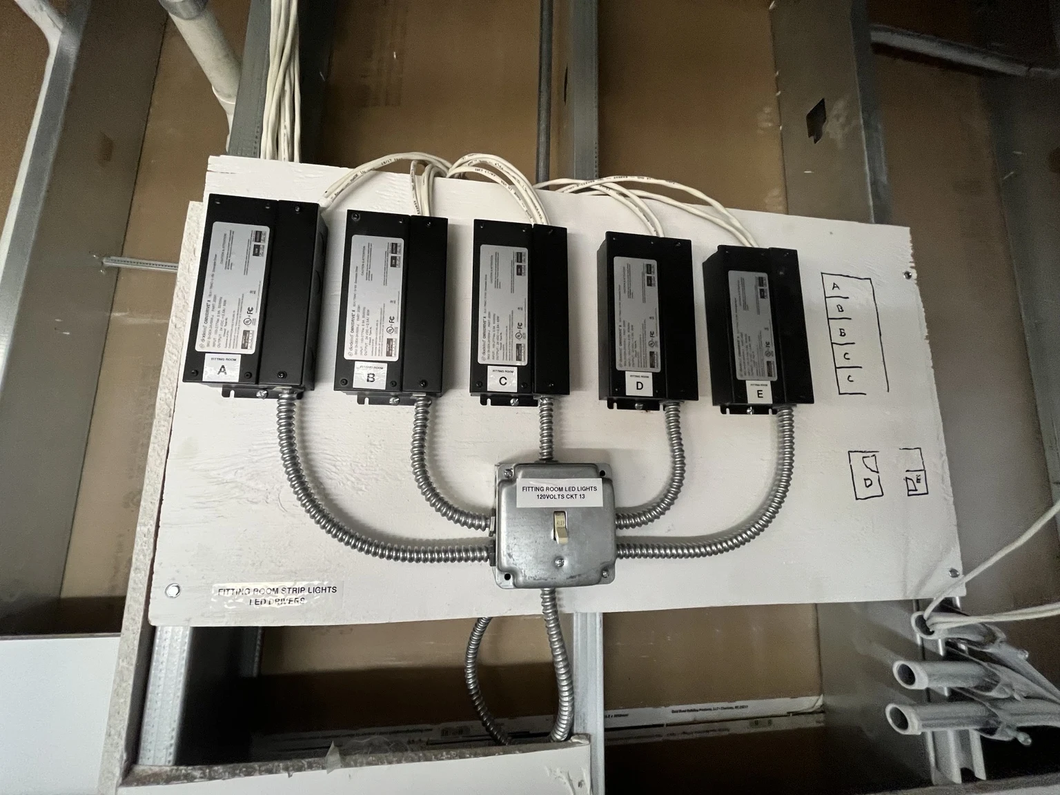 Labeled LED drivers and wiring for fitting room strip lighting.