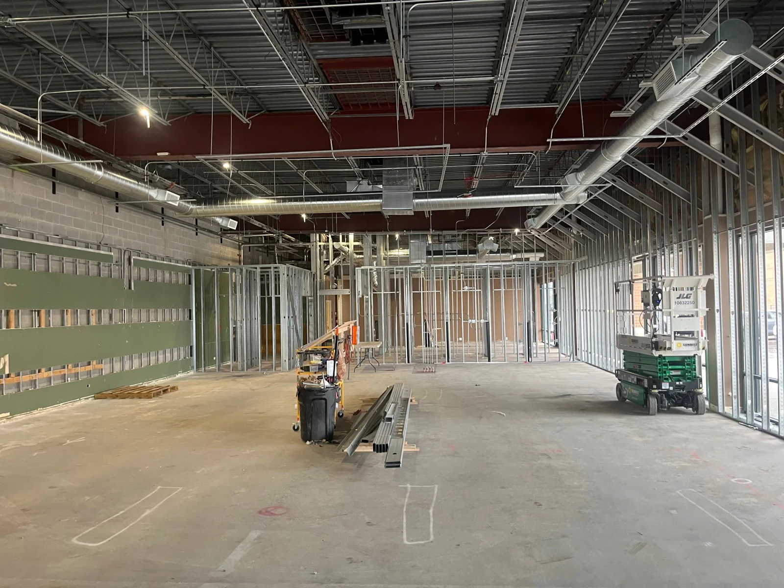 Retail space under construction with exposed framing, overhead conduit and building systems.