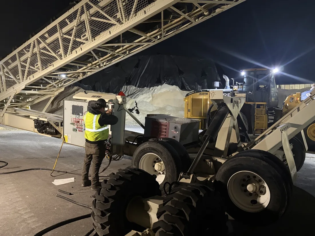 Electrician beside conveyor equipment during an evening service call