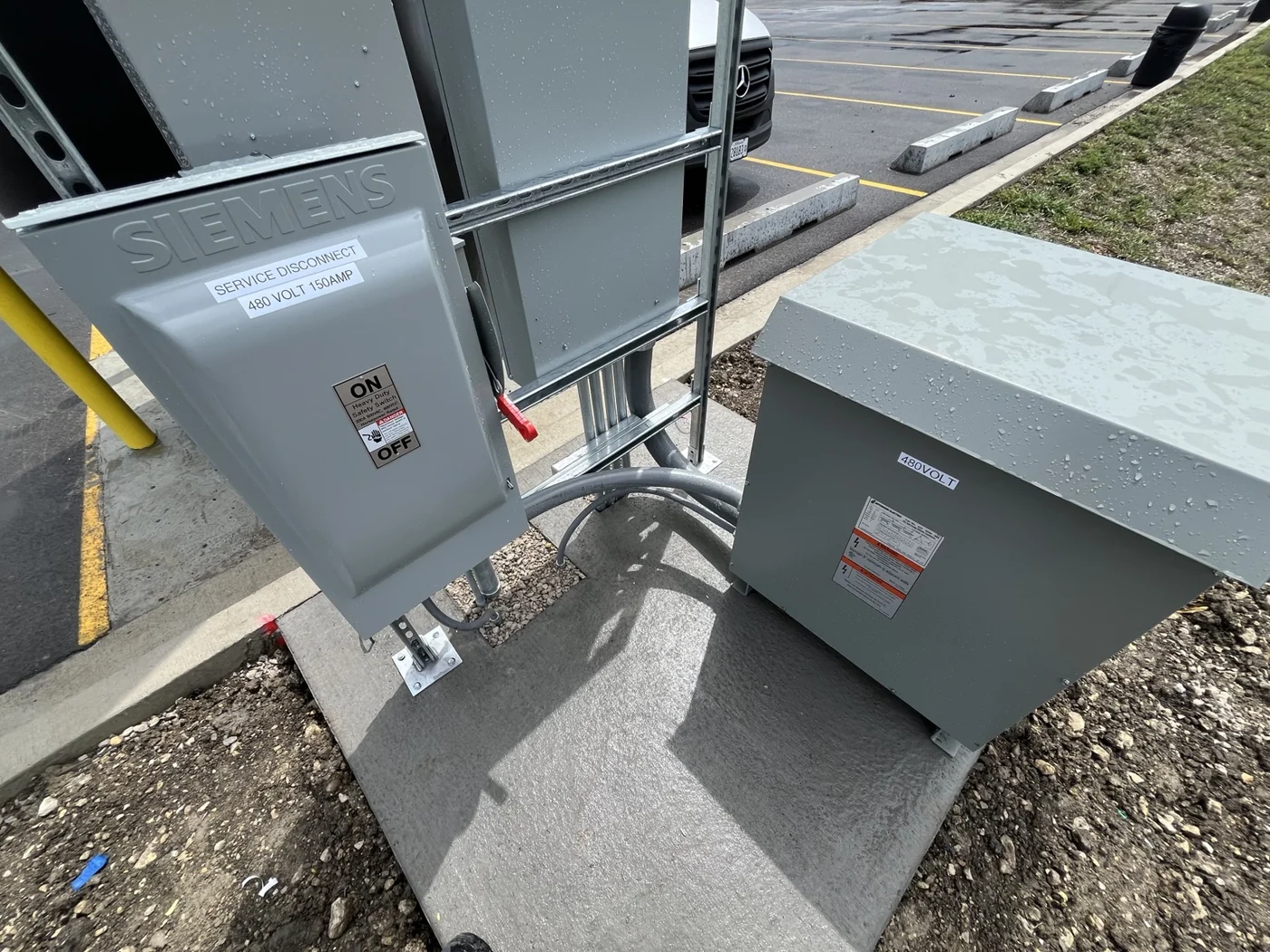 Labeled 150-amp service disconnect and transformer connected by metal conduit at the sign base.