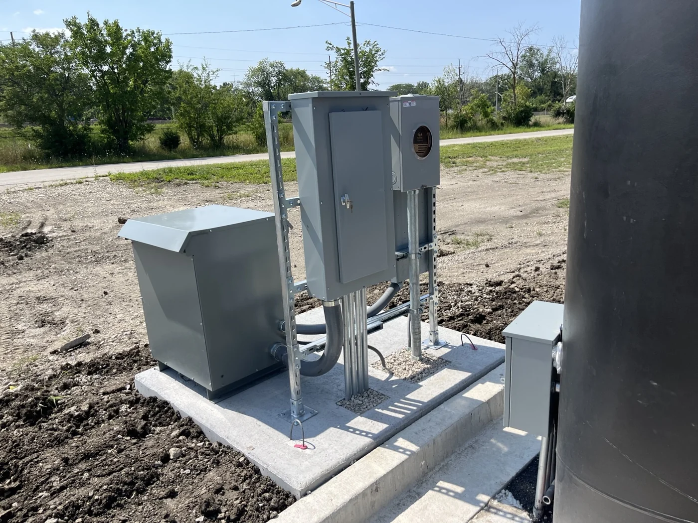 Outdoor transformer and distribution panel mounted beside the sign on a precast concrete pad.