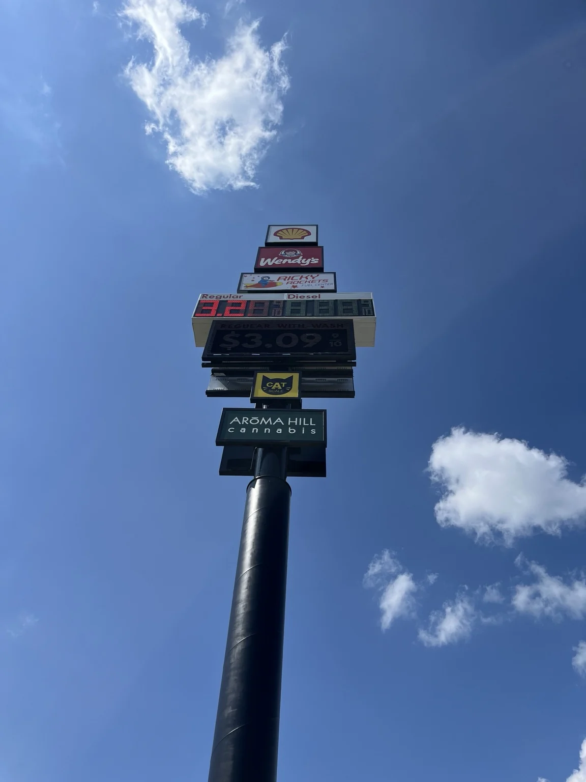 High-rise sign at Ricky Rockets in Kankakee, with illuminated business signs and digital fuel-price displays.