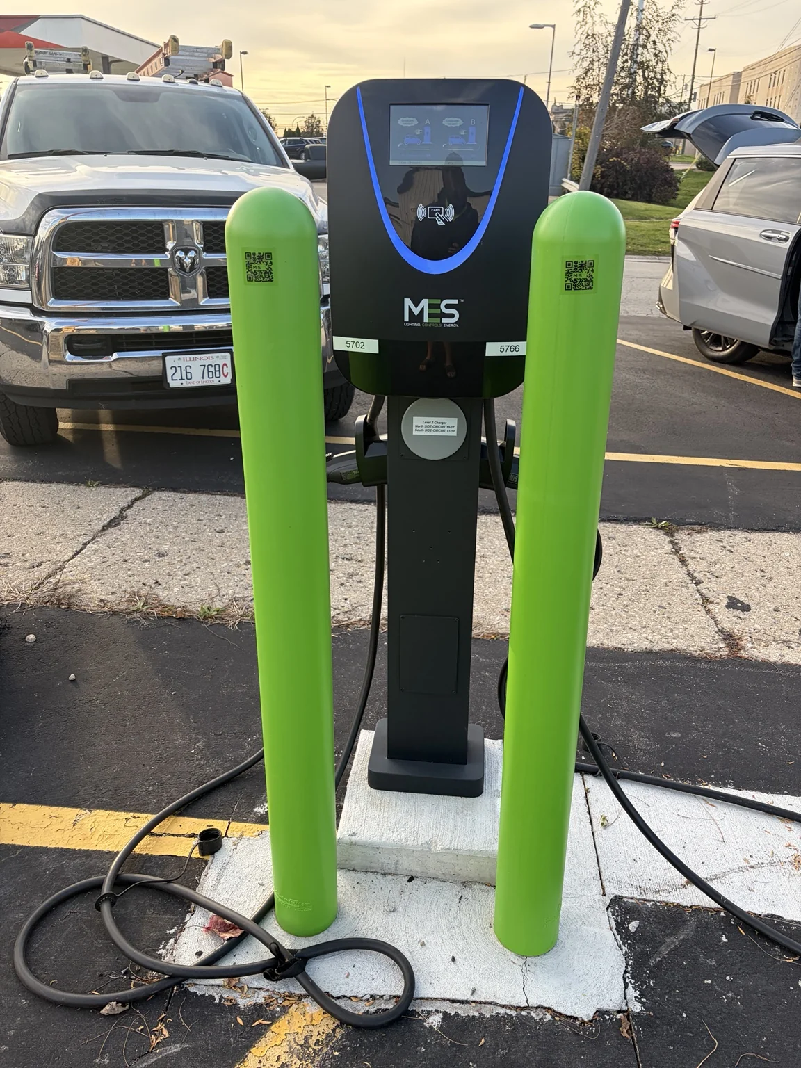 Dual-port Level 2 charger positioned between green bollards.