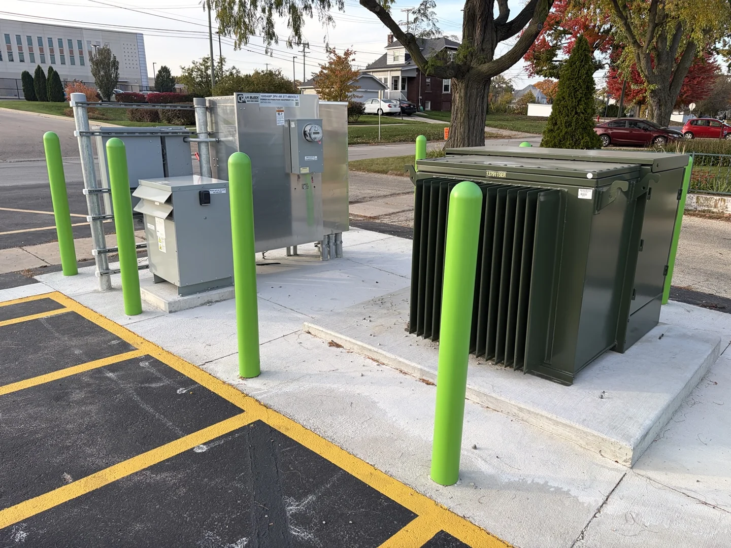 Utility transformer and metering equipment on concrete bases beside marked parking spaces.
