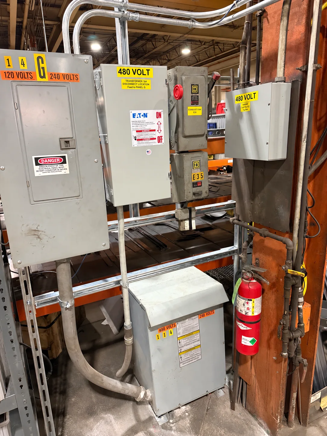 Electrical panel, disconnects, transformer and conduit beside a structural column.