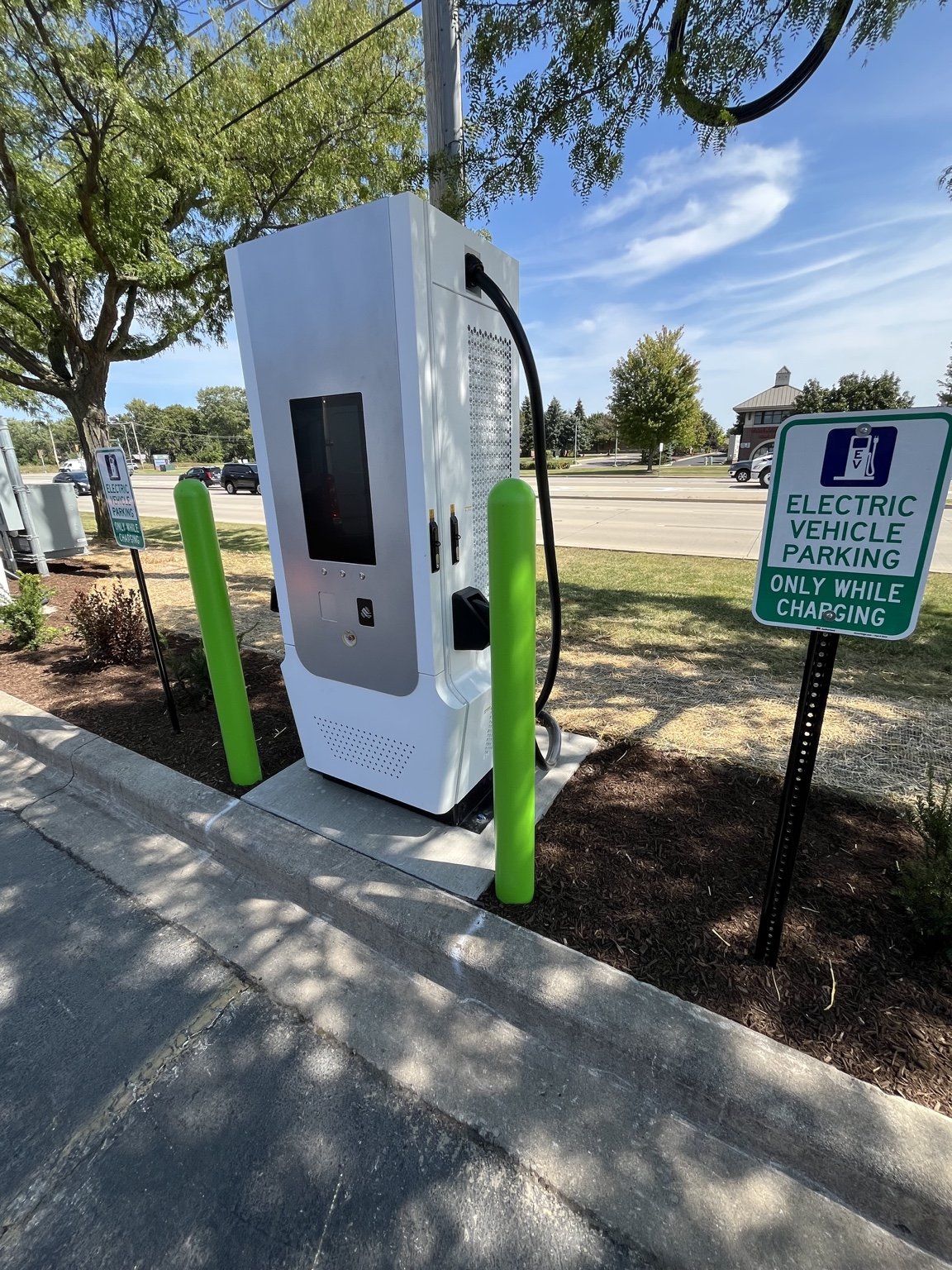 EV charging station with green bollards and a parking sign in Naperville.