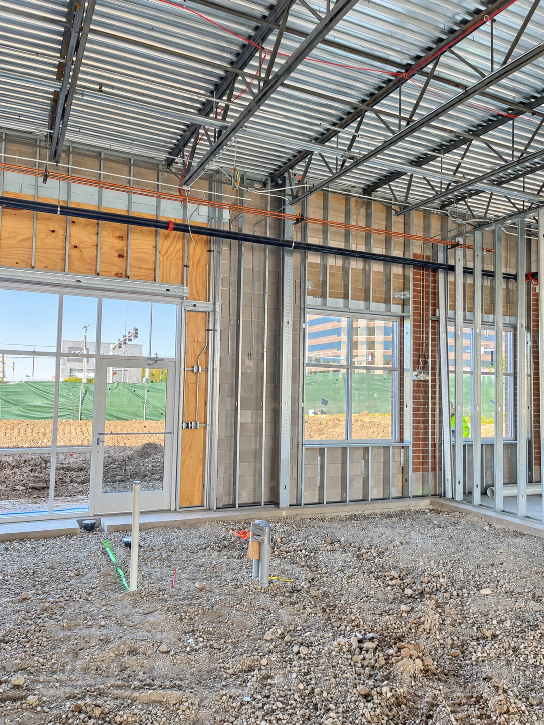 Exposed framing, conduit, and ceiling structure inside a commercial shell space under construction.