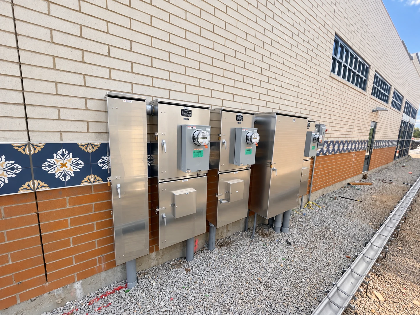 Individual tenant metering cabinets, disconnect enclosures, and associated equipment on a commercial building exterior.