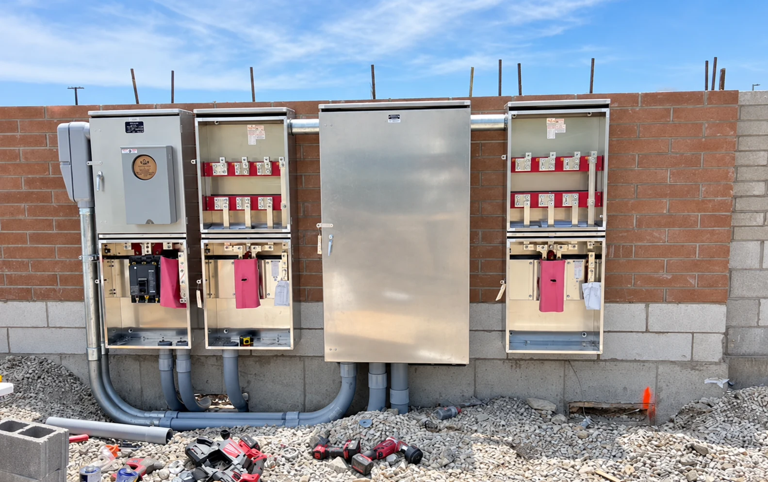 Metering and disconnect equipment with covers open during construction beside a central cabinet.
