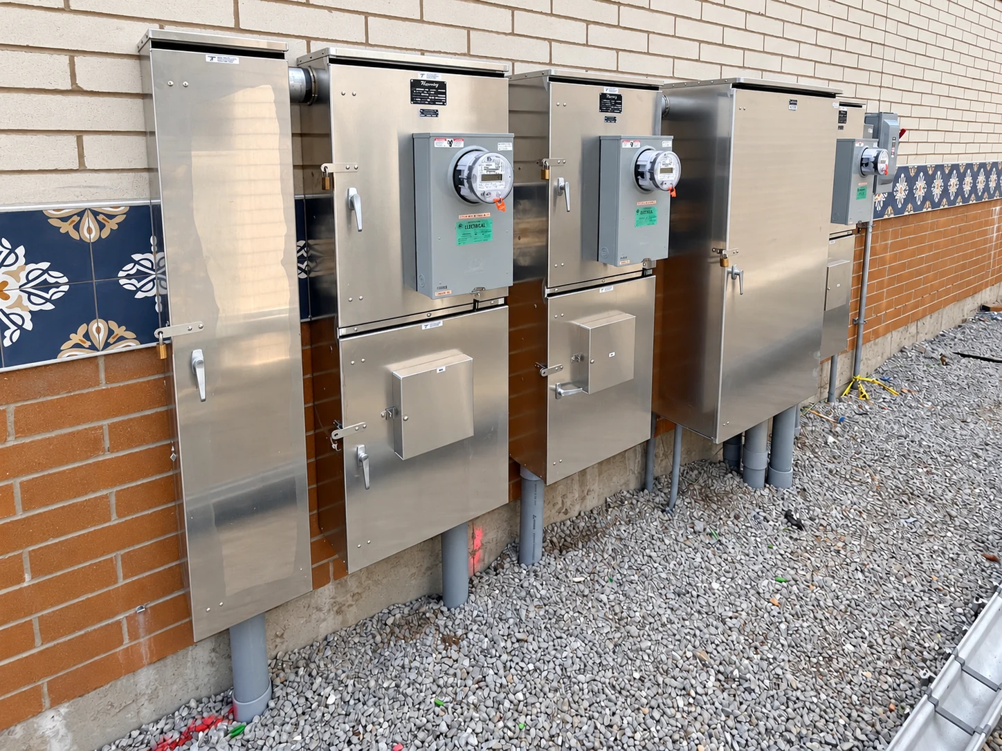 Close view of individual metering cabinets and disconnect enclosures along the building wall.