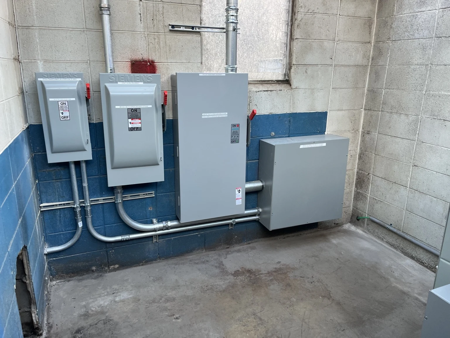 Wall-mounted disconnect switches and conduit in the Polar Dome electrical room.