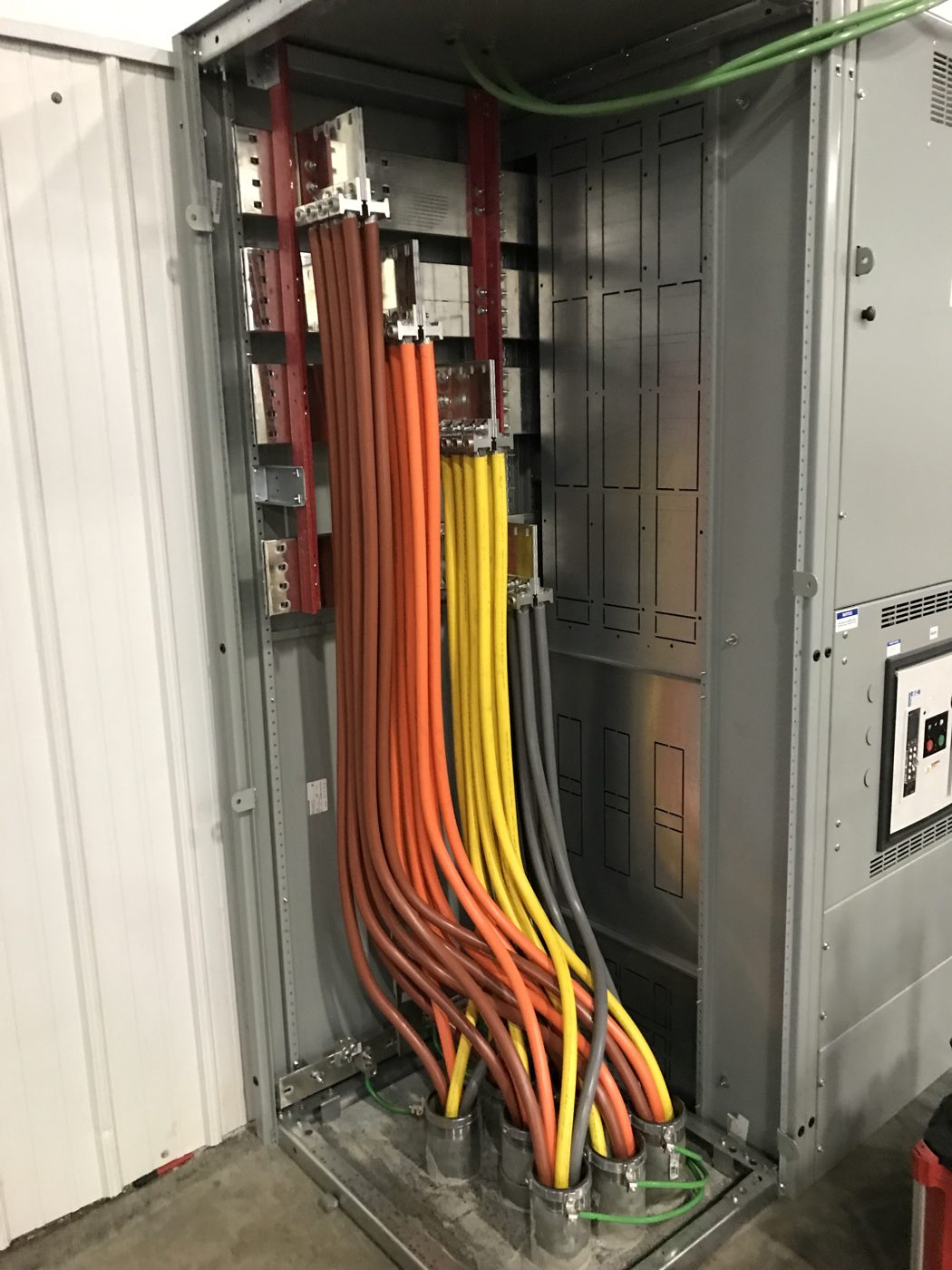 Color-coded conductors inside electrical service equipment during installation.