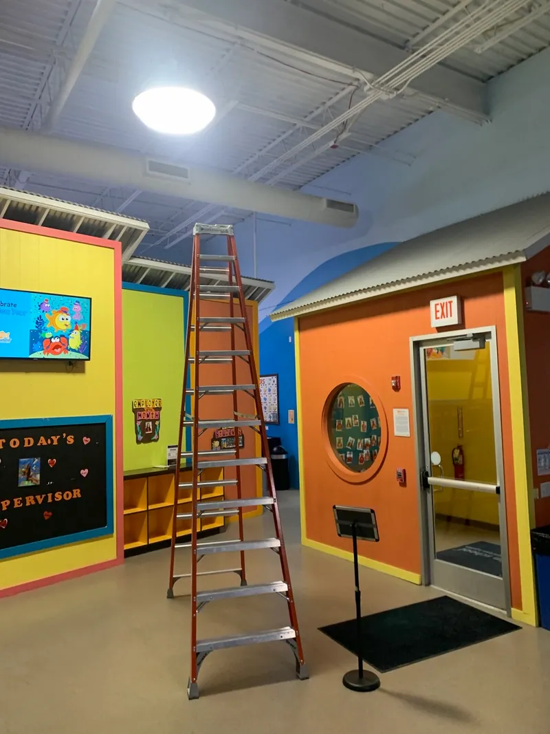 Stepladder beneath an illuminated ceiling fixture near a swim school entrance