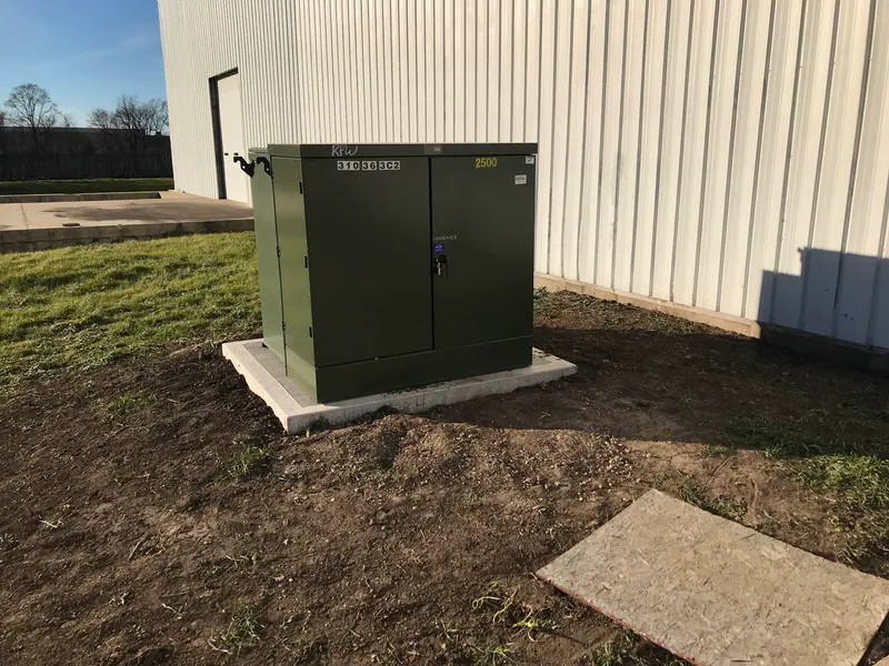 Exterior utility transformer installed on the new precast concrete pad.