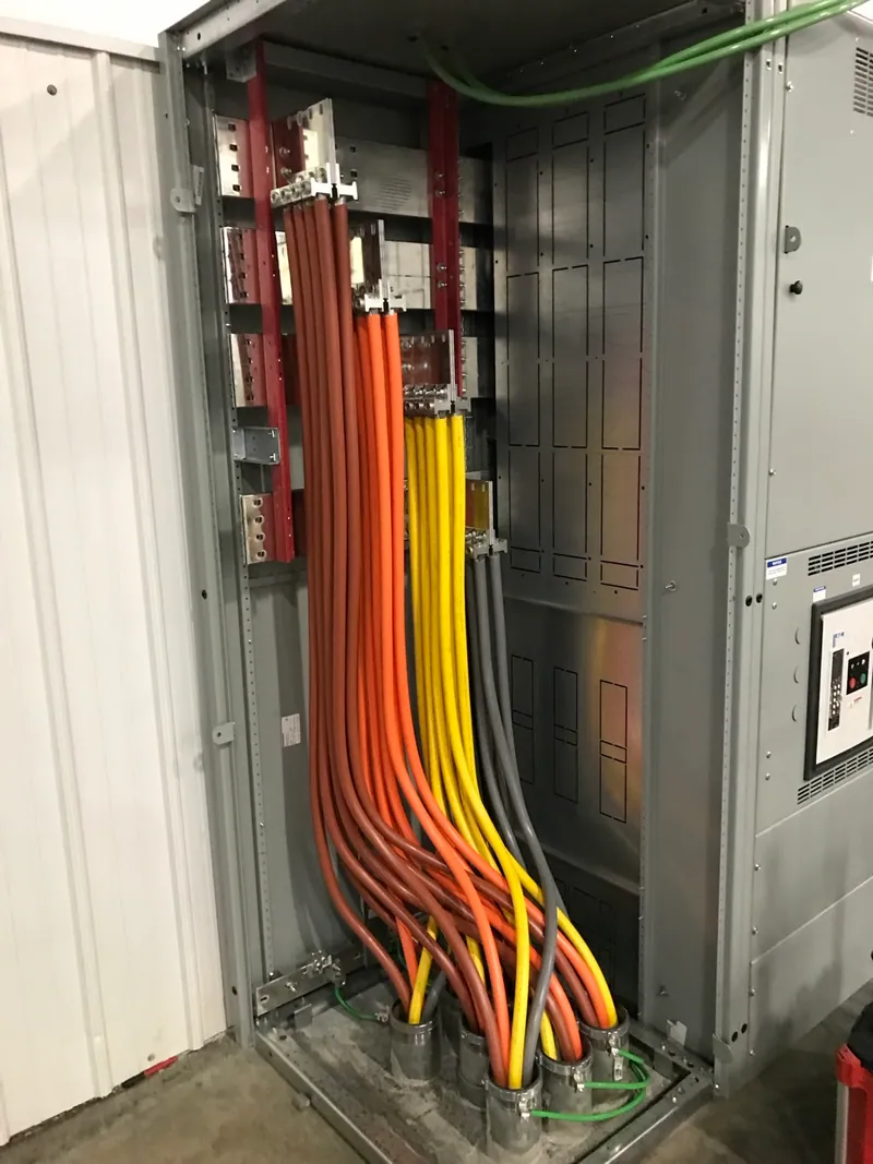 Parallel service conductors routed and terminated inside the switchboard’s utility connection section.