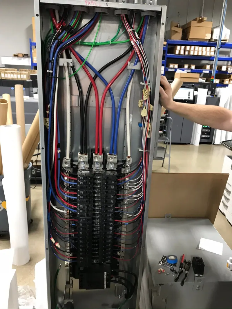 Open electrical distribution panel showing conductors and branch circuits during installation