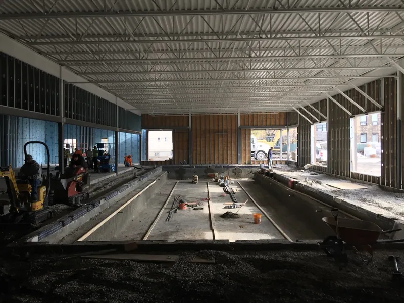 Indoor pool under construction with exposed wall framing and roof structure