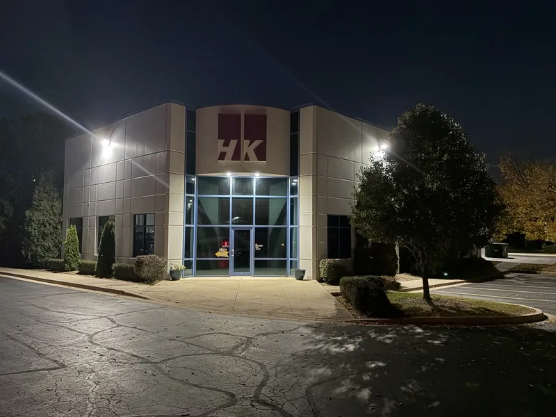 HK Laser building at night with illuminated exterior walls and entrance canopy in Bartlett, Illinois