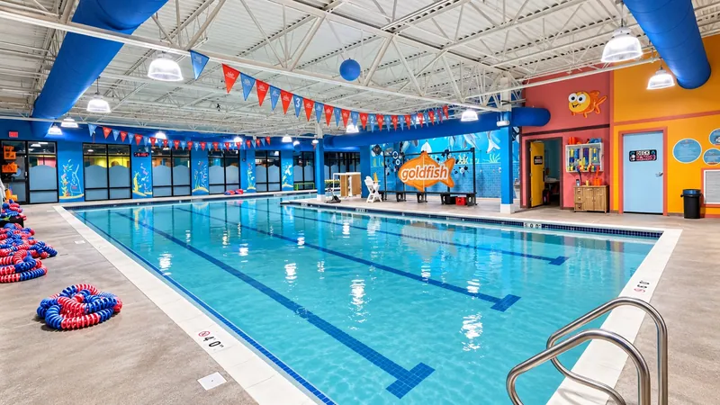 Indoor Goldfish Swim School pool with suspended lights, blue ductwork, and branded wall mural