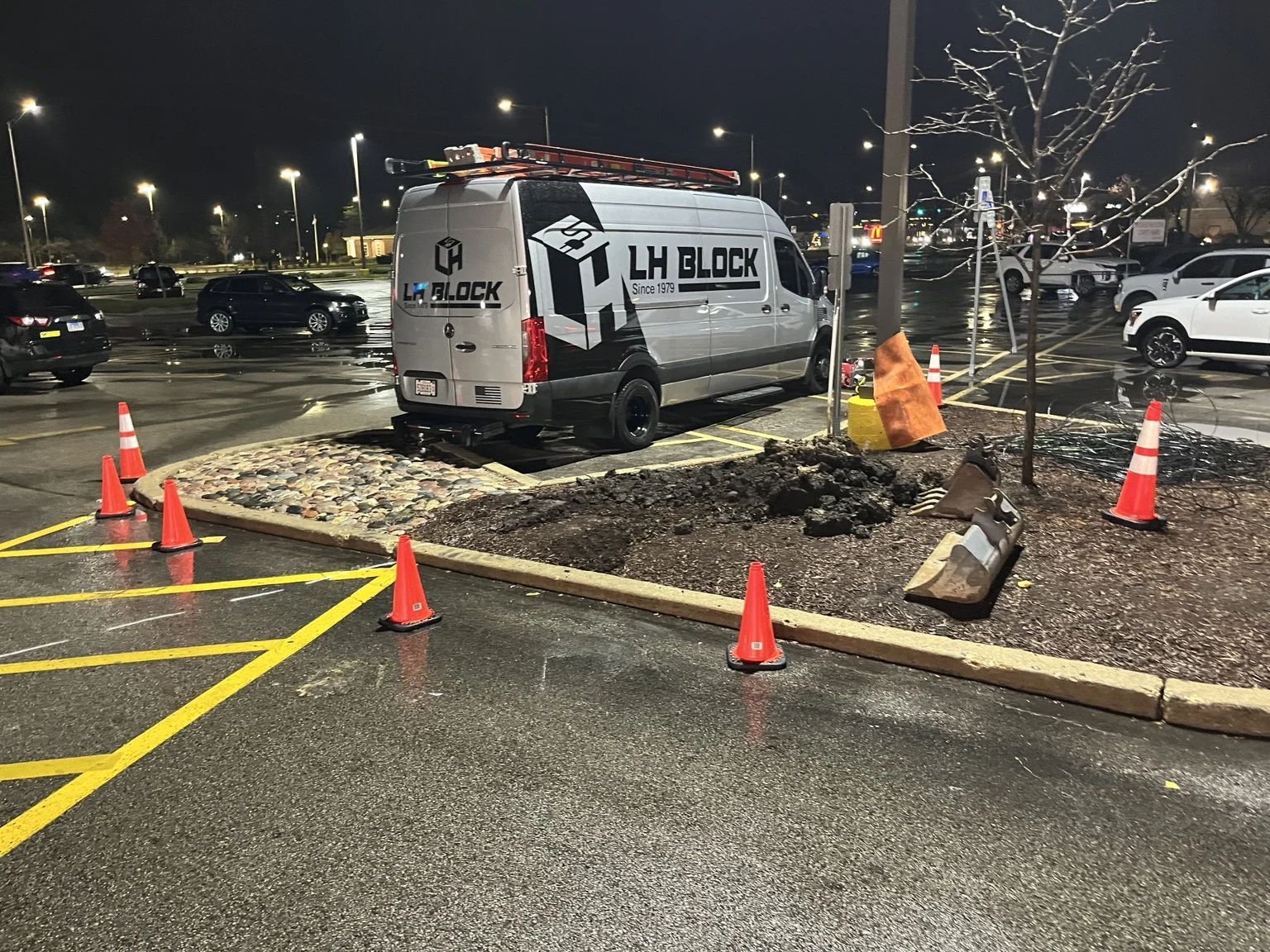 LH Block Electric working at the parking-lot island after dark.