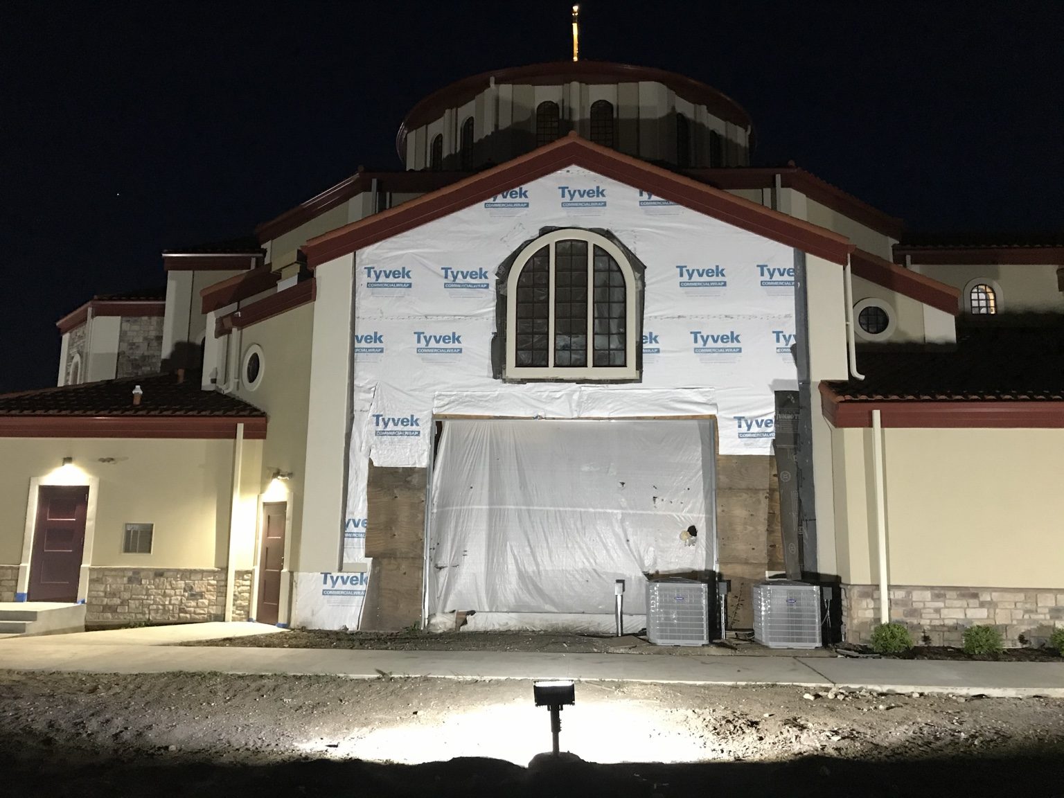 Illuminated church exterior with building wrap visible during construction.