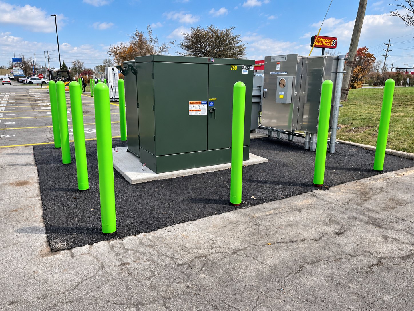 Green transformer enclosure surrounded by protective bollards at the Villa Park EV project.