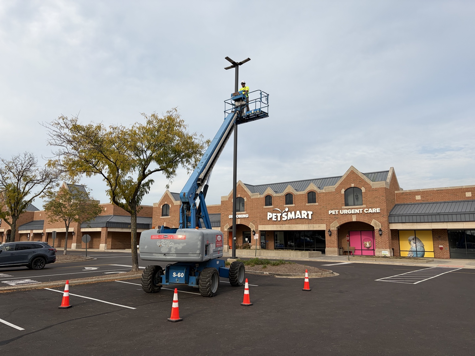 Electrician working at a parking-lot fixture from a boom lift near PetSmart.