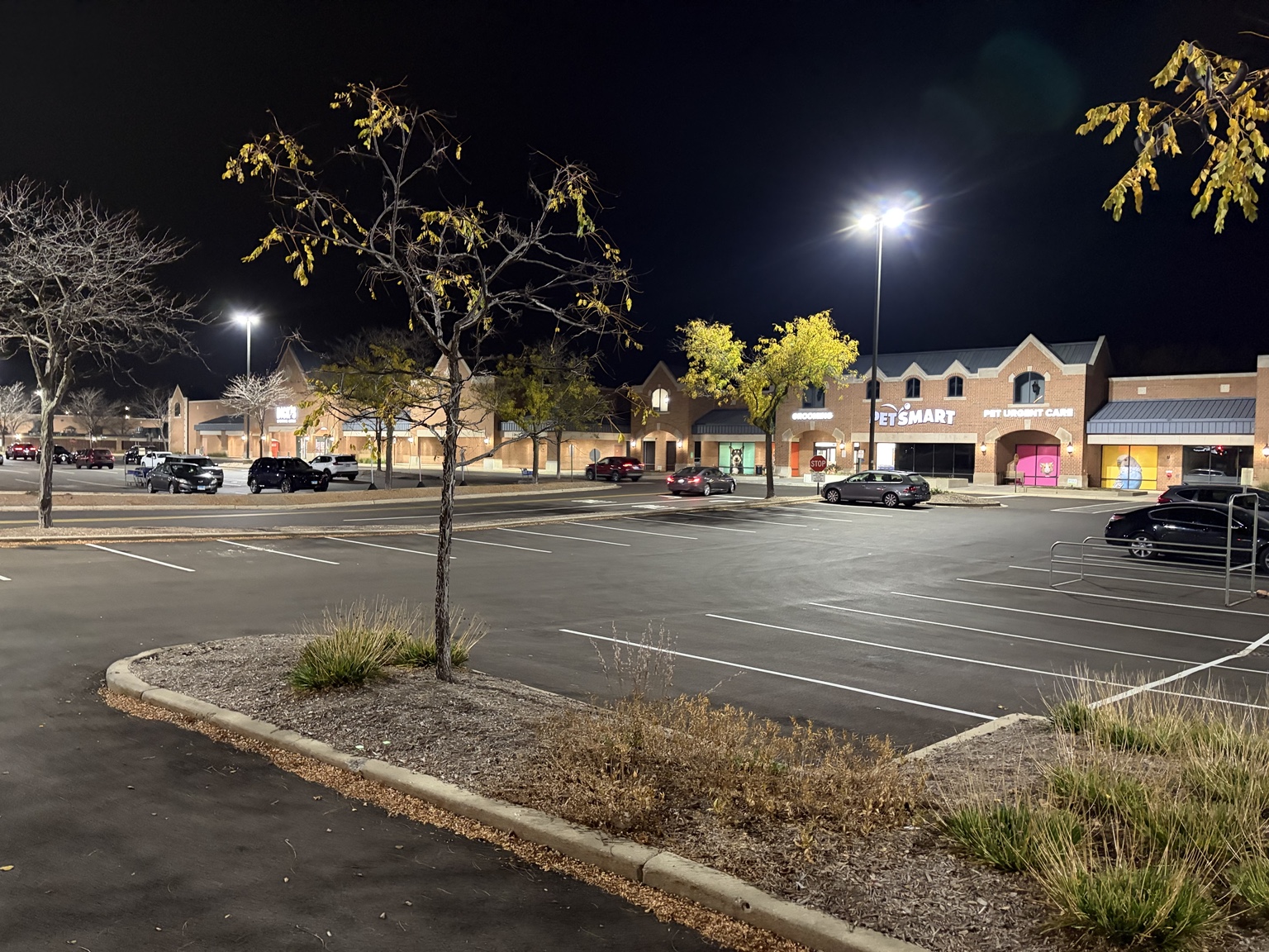Nighttime view of the illuminated parking areas and storefronts at Village Square of Northbrook.