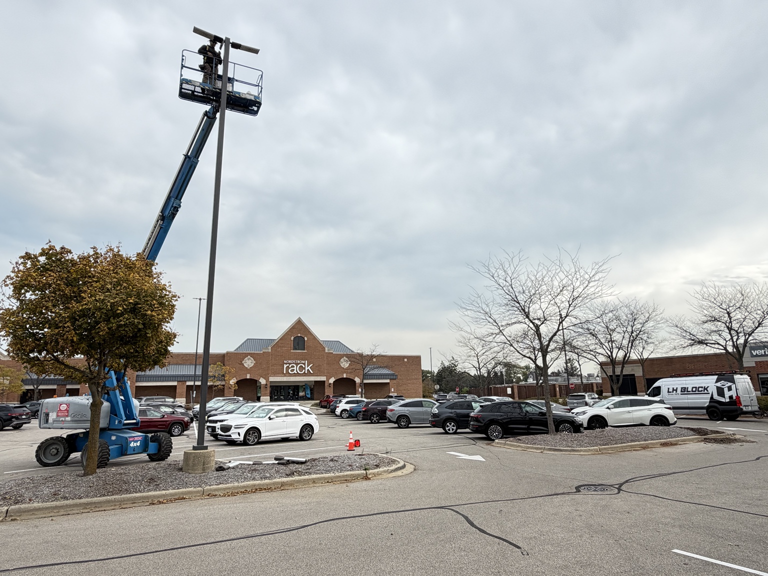 Lighting installation in the parking area near Nordstrom Rack, with an LH Block service van on site.