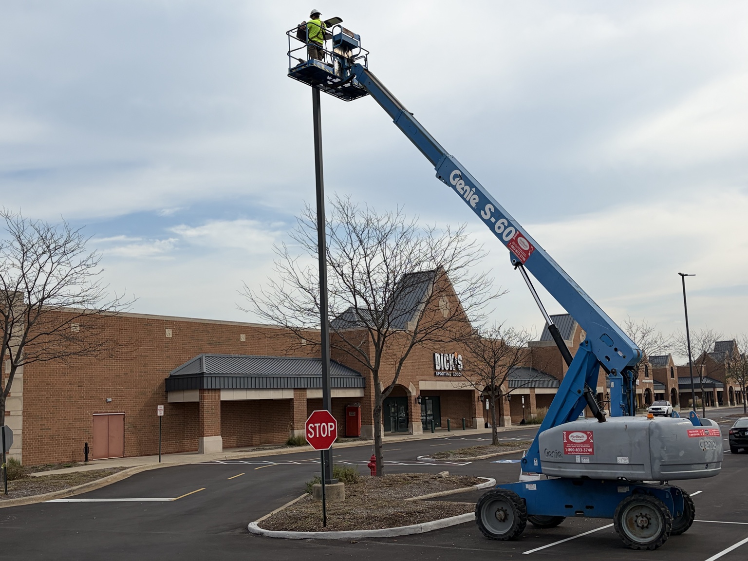 Boom lift positioned at a parking-lot light pole near Dick’s Sporting Goods.